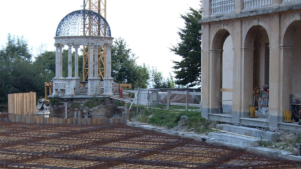 Belvedere circolare e facciata porticata accanto al solaio in armatura durante il cantiere.