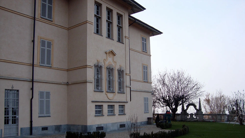 Facciata laterale della villa ottocentesca accanto al prato e alla balaustra del giardino.