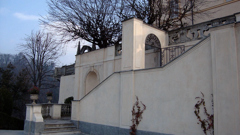 Scala esterna in pietra integrata nella muratura decorata del giardino della villa.